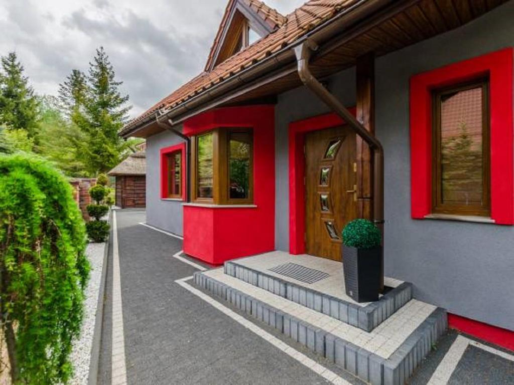 une porte d'entrée rouge d'une maison avec une terrasse couverte dans l'établissement Dom nad jeziorem Ublik z sauną i jacuzzi, à Ublik