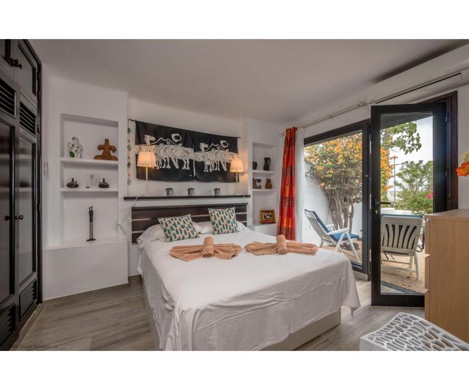 a bedroom with a large white bed and a balcony at Puerto Chico I and J in Playa Blanca