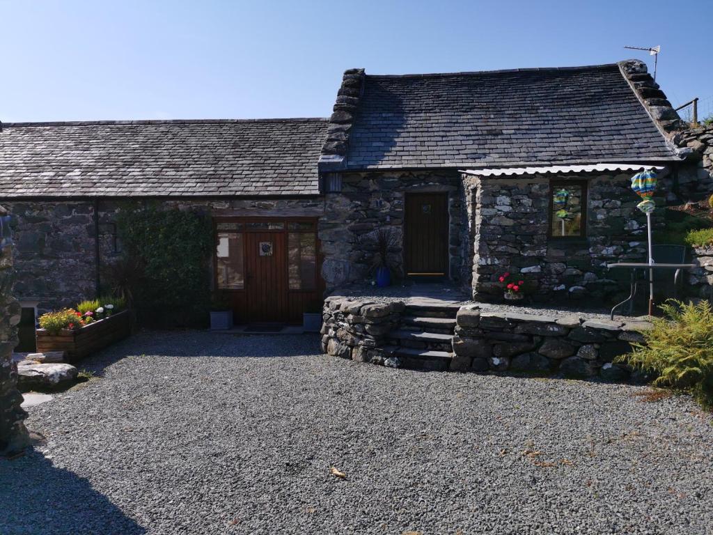 uma casa de pedra com uma entrada de pedra em frente em Ty Gwennol near Gilfach Goch em Llanbedr