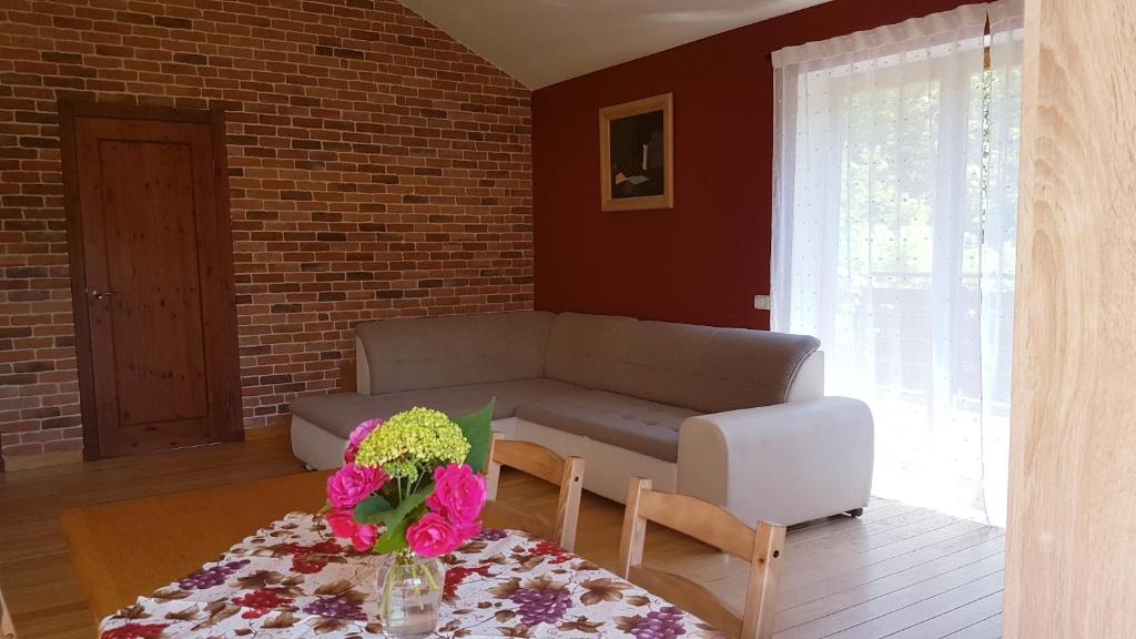ein Wohnzimmer mit einem Sofa und einem Tisch mit Blumen in der Unterkunft Cozy Corner in Saulkrasti