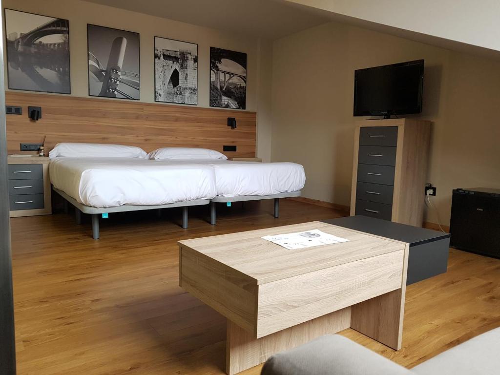 pokój z dwoma łóżkami, stołem i telewizorem w obiekcie Apartamentos Turísticos y Habitaciones Cidade Vella by Bossh! Hotels w mieście Ourense