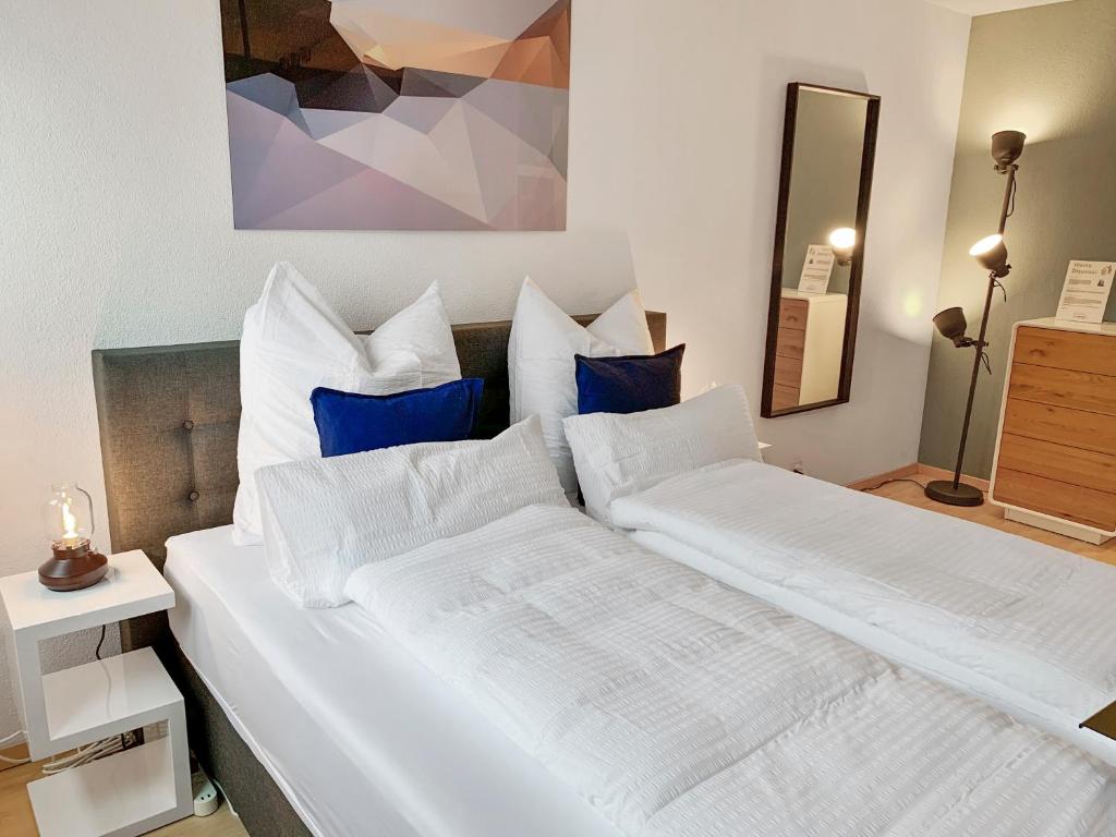 2 weiße Betten in einem Schlafzimmer mit blauen Kissen in der Unterkunft ARISER - City View 1 Business Apartment in Zug