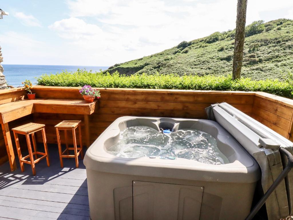 a hot tub on a deck with a view of the ocean at 2 Cliff Cottages in Truro