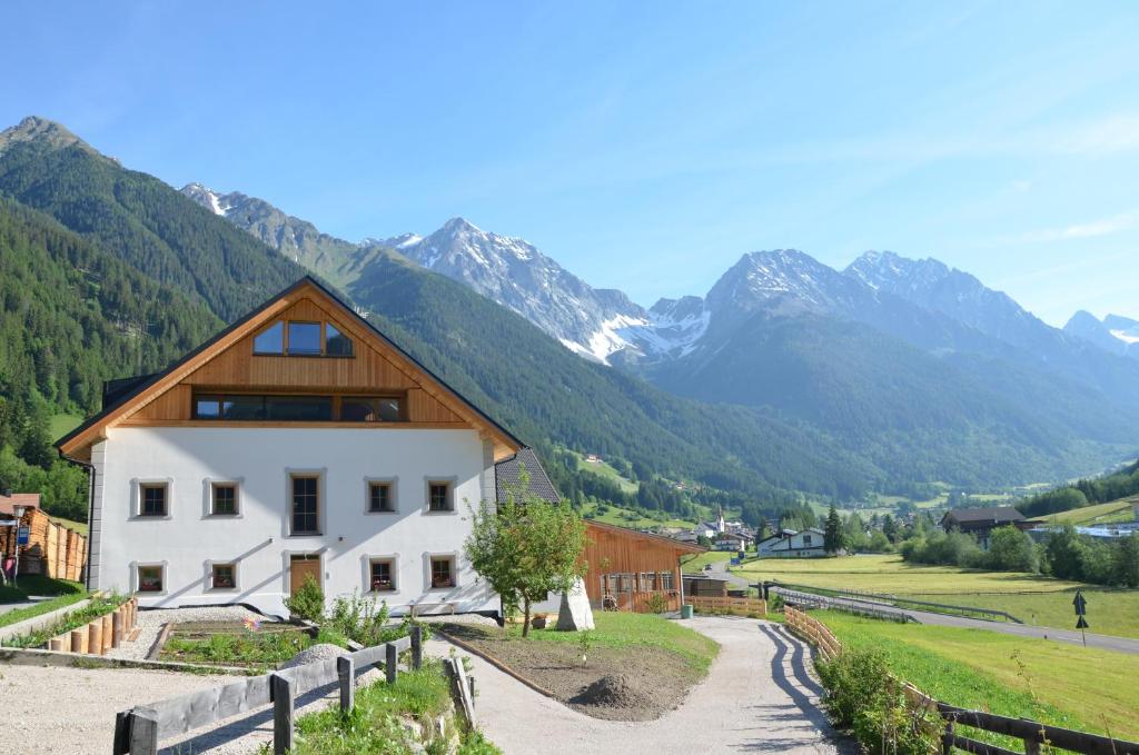 a white house with a wooden roof with mountains in the background at Ausserwegerhof in Anterselva di Mezzo