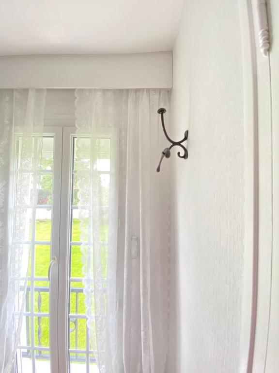 a window with white curtains and a hanger at LE VIEUX MOULIN in Bouhet