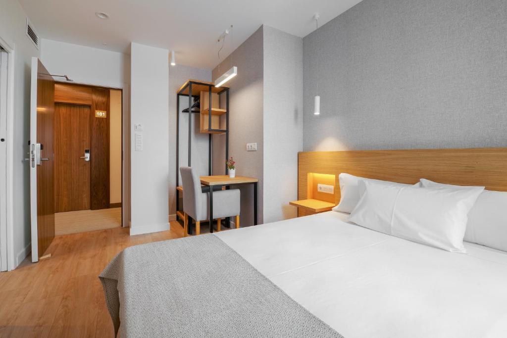 1 dormitorio con cama blanca y escritorio en Hotel Condado Ourense, en Ourense