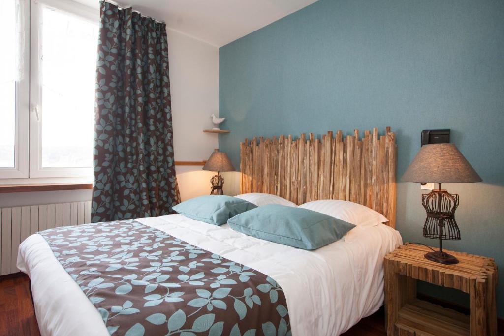 a bedroom with a large bed with blue walls at Hotel Logis Beauséjour in Erquy