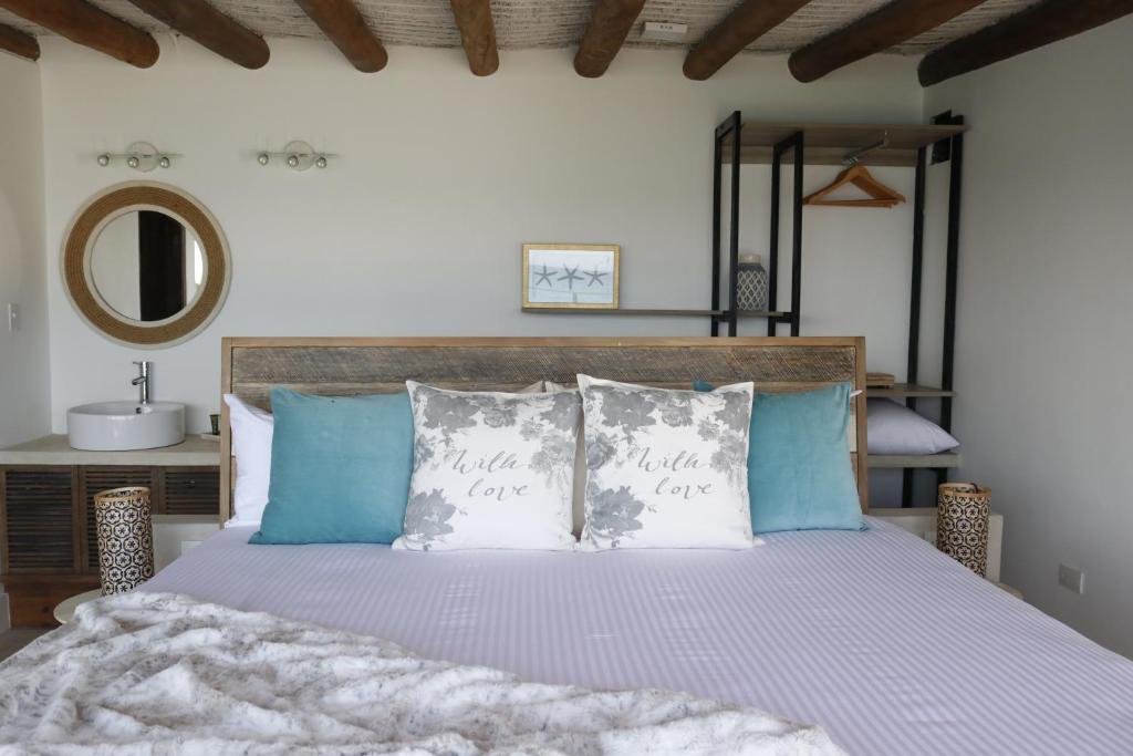 1 dormitorio con 1 cama con almohadas azules y blancas en Aria By LD Hotel Boutique en Pampatar