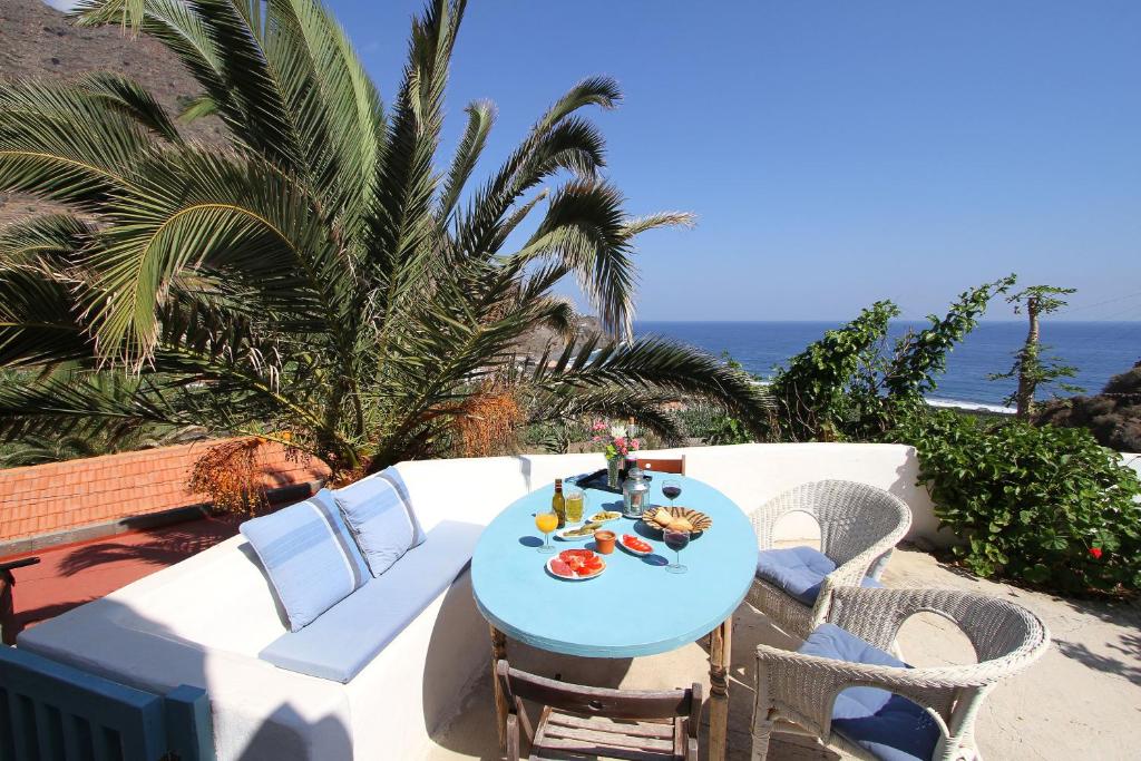 Casa Rural Vista del Mar في إرميغوا: طاولة زرقاء وكراسي على فناء مع المحيط