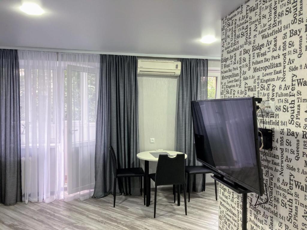 sala de estar con TV y mesa con sillas en White&Grey apartment, en Vínnytsia