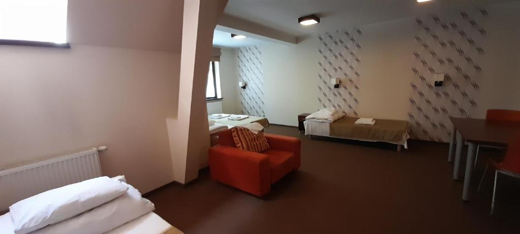 コシチェジナにあるWilla Strzelnicaのベッド2台と赤い椅子が備わる客室です。
