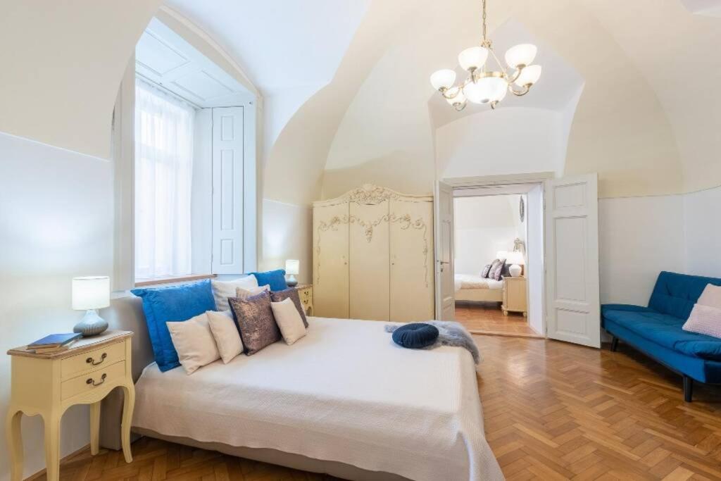 ein Schlafzimmer mit einem großen Bett und einem blauen Sofa in der Unterkunft ROSE APARTMENTS / ROMANTIC & COZY / CITY CENTER in Prag