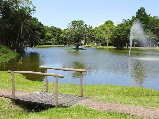 uma ponte de madeira sobre um lago com uma fonte em Eden wilds J124 em Port Edward