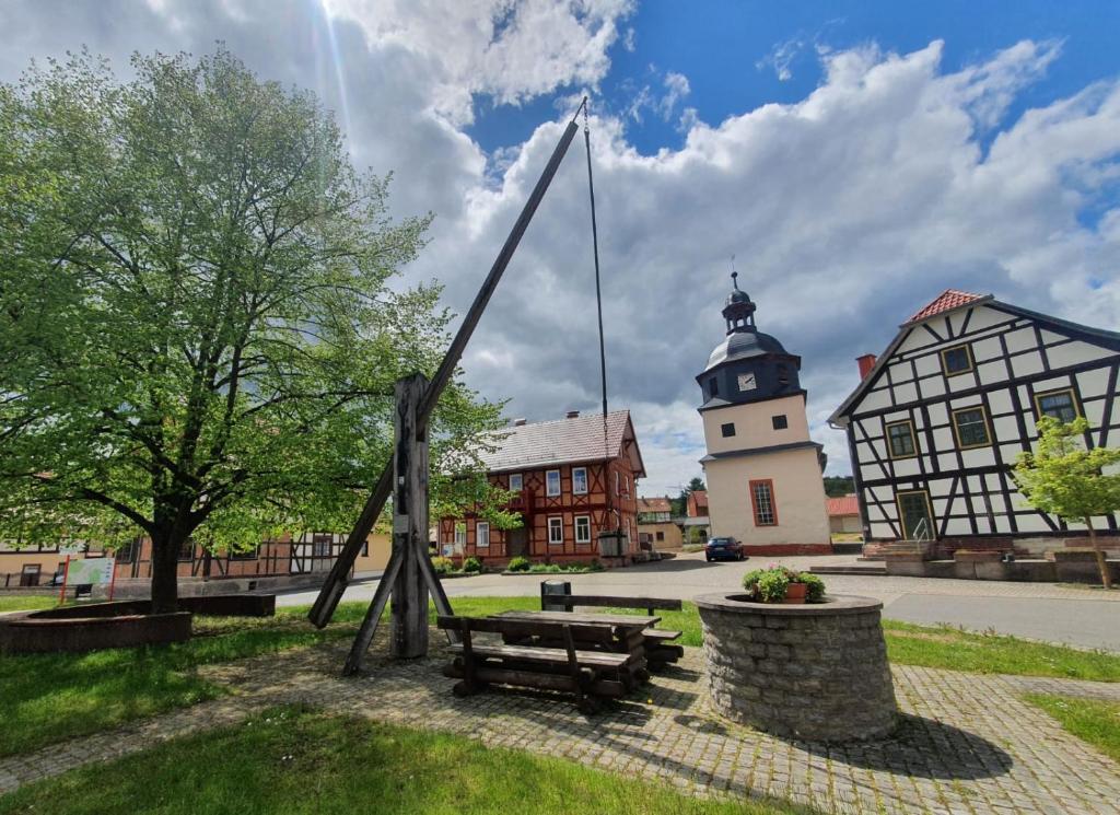 un parc avec un banc et un bâtiment avec une tour dans l'établissement Altes Pfarrhaus Neustädt, à Neustädt