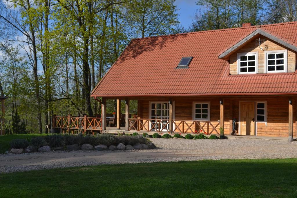 Casa de madera con techo rojo y patio en Sodyba Širvynė, en Užpaliai