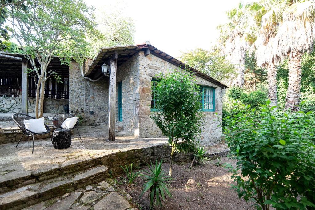 une maison en pierre avec 2 chaises et une terrasse couverte dans l'établissement Neiva River House - Azenha Next to the River, à Esposende