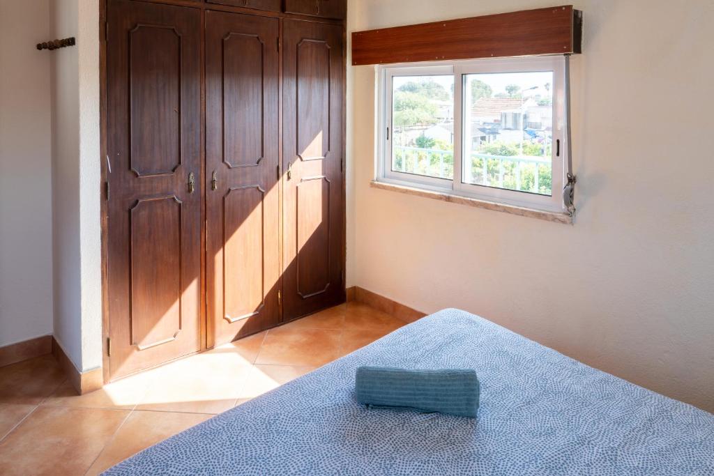 a bedroom with a window and a bed with a blue blanket at Natural Mystic Hostel in Costa da Caparica