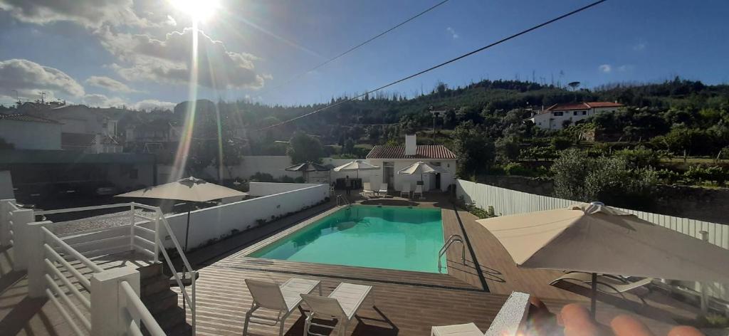 uma piscina num deque com cadeiras e guarda-sóis em Hotel Pantanha Nature & Fitness em Caldas da Felgueira