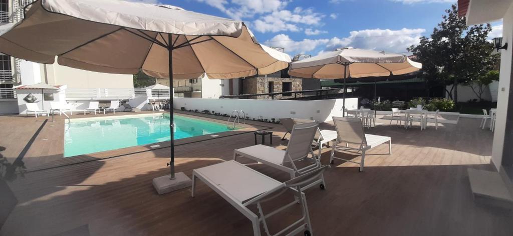 uma piscina com cadeiras e guarda-sis numa varanda em Hotel Pantanha Nature & Fitness nas Caldas da Felgueira