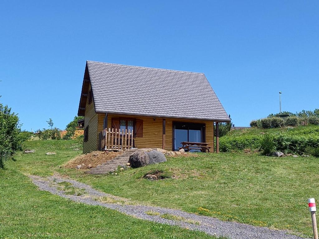 a small cabin in a grassy field with a path leading to it at Chalet Sancy in Saint-Genès-Champespe