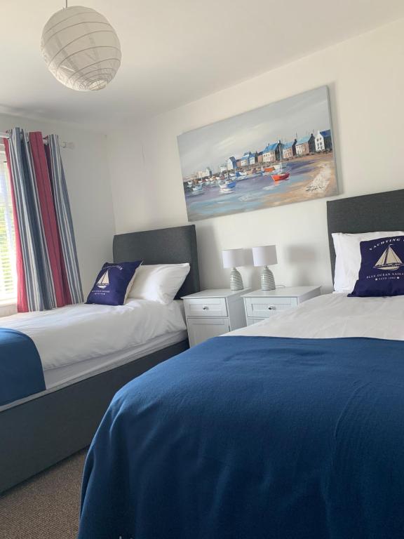 a bedroom with two beds and a painting on the wall at Lovely well equipped apartment - 2 bedroom, sleeps 4, sundeck, 8 min river walk to beach and town, FREE parking permit ! in Lyme Regis