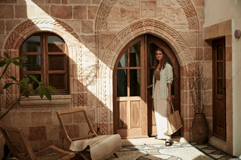 une femme debout à l'entrée d'un bâtiment dans l'établissement AF Lindia Nature Design Hotel, à Lindos