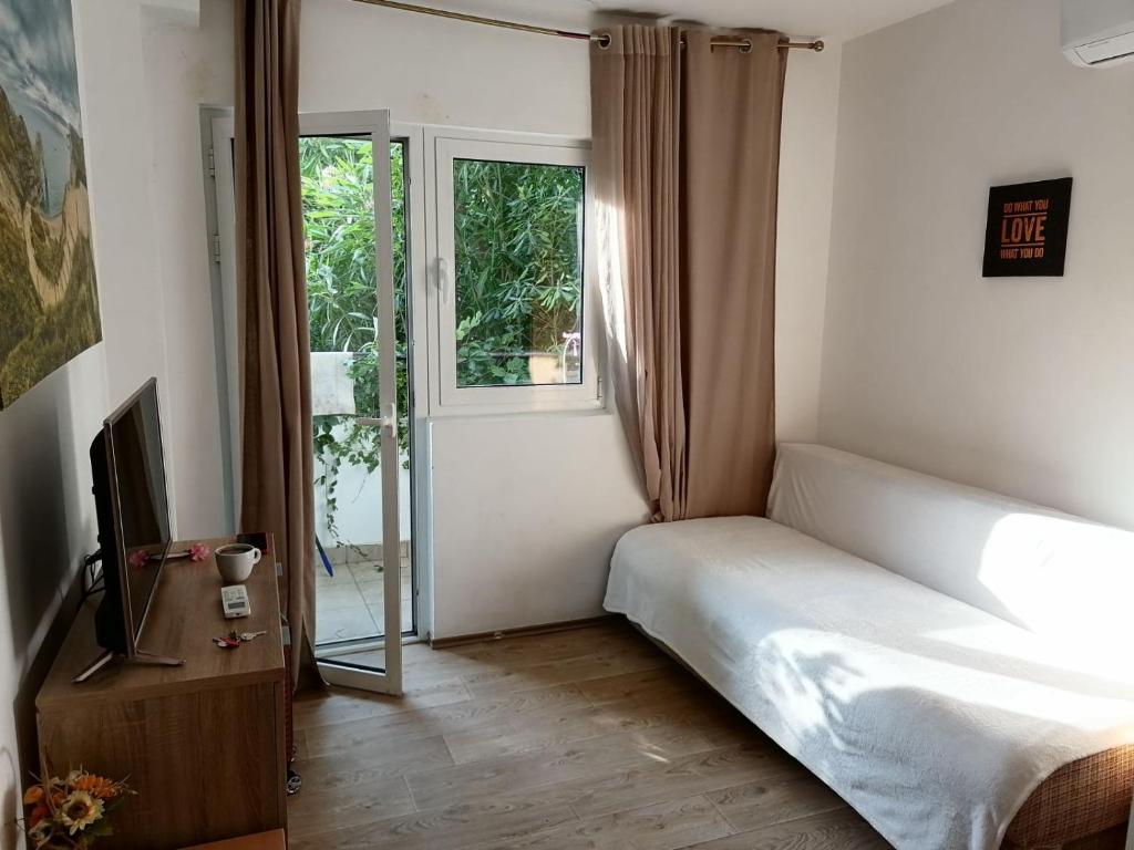 Schlafzimmer mit einem Bett, einem TV und einem Fenster in der Unterkunft Candy apartment central location Bečići in Becici