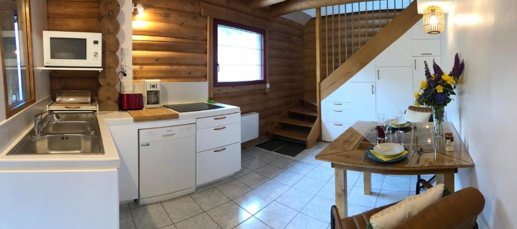 a kitchen with white cabinets and a table in a room at Neizhig Koad Petit Nid en Bois in Péaule