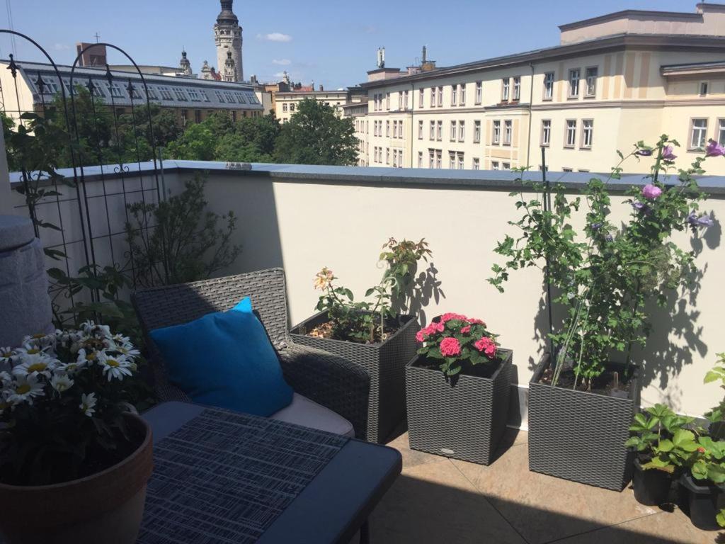 einen Balkon mit Stühlen und Topfpflanzen auf einem Gebäude in der Unterkunft LUXUSAPPARTEMENT mitten in Leipzig Neueröffnung ! in Leipzig