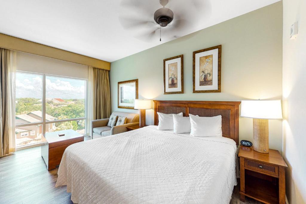 デスティンにあるLuau Condos IIのベッドと大きな窓が備わるホテルルームです。