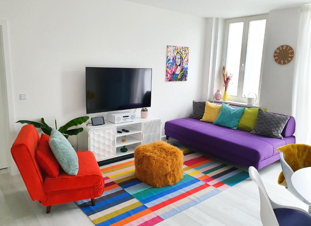 ein Wohnzimmer mit 2 bunten Stühlen und einem TV in der Unterkunft PB Ferienwohnungen - FeWo 6 - Stilvoll eingerichtetes Apartment im Herzen Senftenbergs in Senftenberg