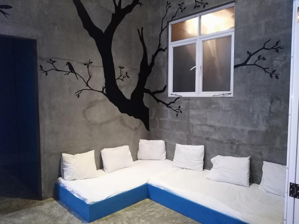 a room with a couch with a tree mural on the wall at Cycling Backpacker Hostel in Unawatuna