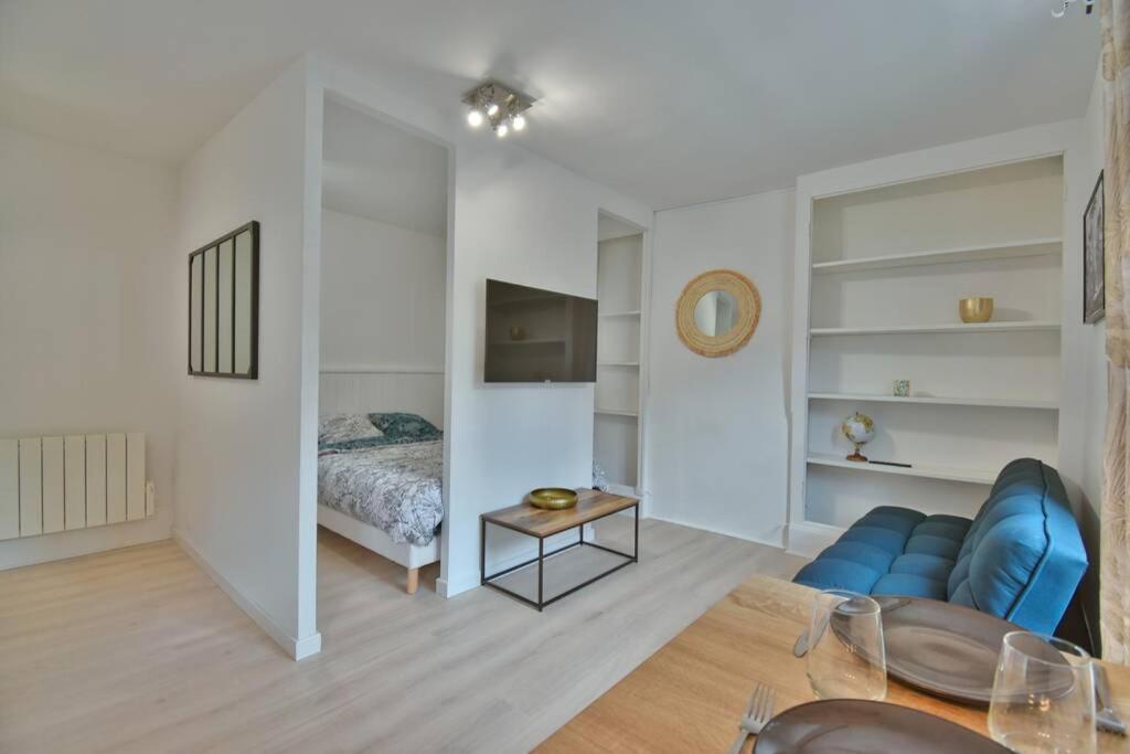 ein Wohnzimmer mit einem blauen Sofa und einem Bett in der Unterkunft Le SWEETHOME in Épernon