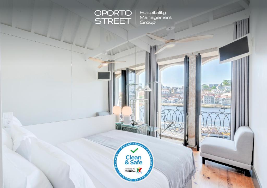 a white bedroom with a bed and a balcony at Oporto Street Fonte Taurina - Riverfront Suites in Porto