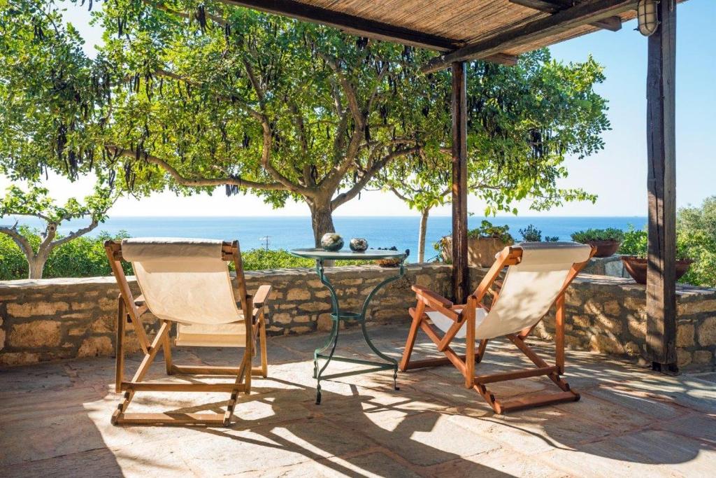 2 Stühle und ein Tisch auf einer Terrasse mit Meerblick in der Unterkunft Villa Venus in Avlemonas