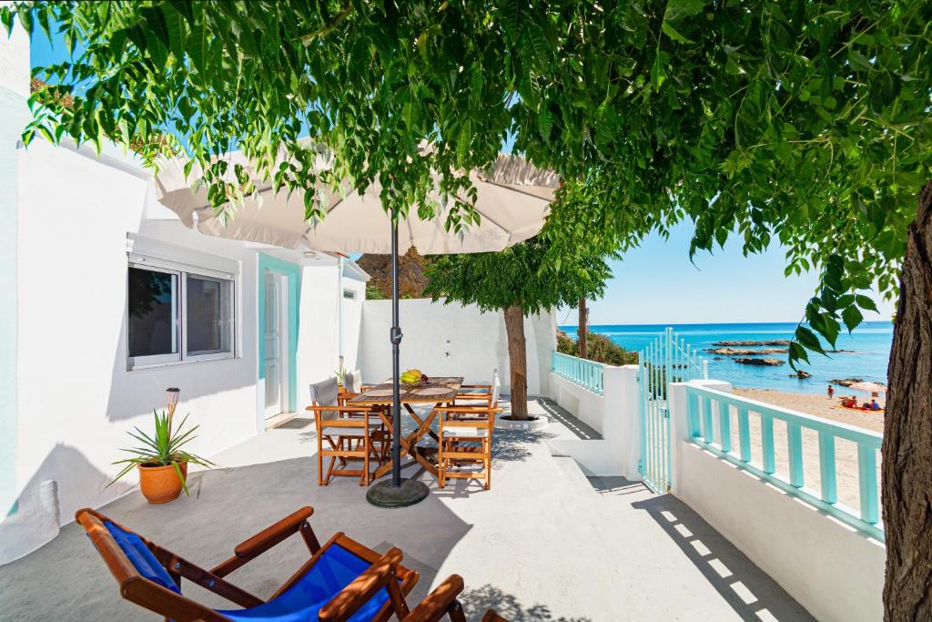 een patio met stoelen en een parasol en de oceaan bij Casa al mare in Archangelos