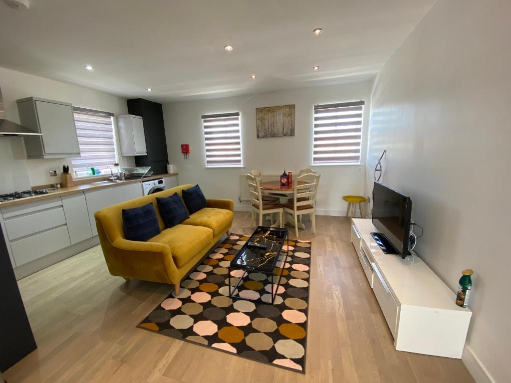 a living room with a yellow couch and a kitchen at Apartment No 8 - Stay in style in the heart of the Cathedral City. in Truro