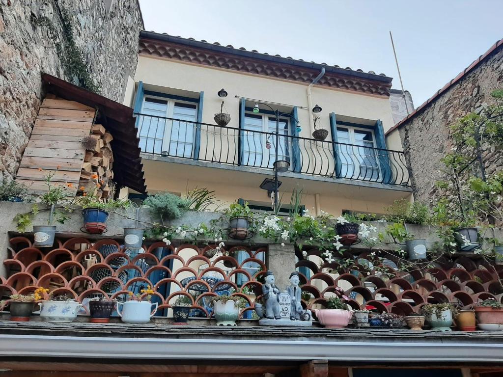 a building with a bunch of potted plants on a ledge at Les Chambres Chouettes in Villefranche-de-Conflent