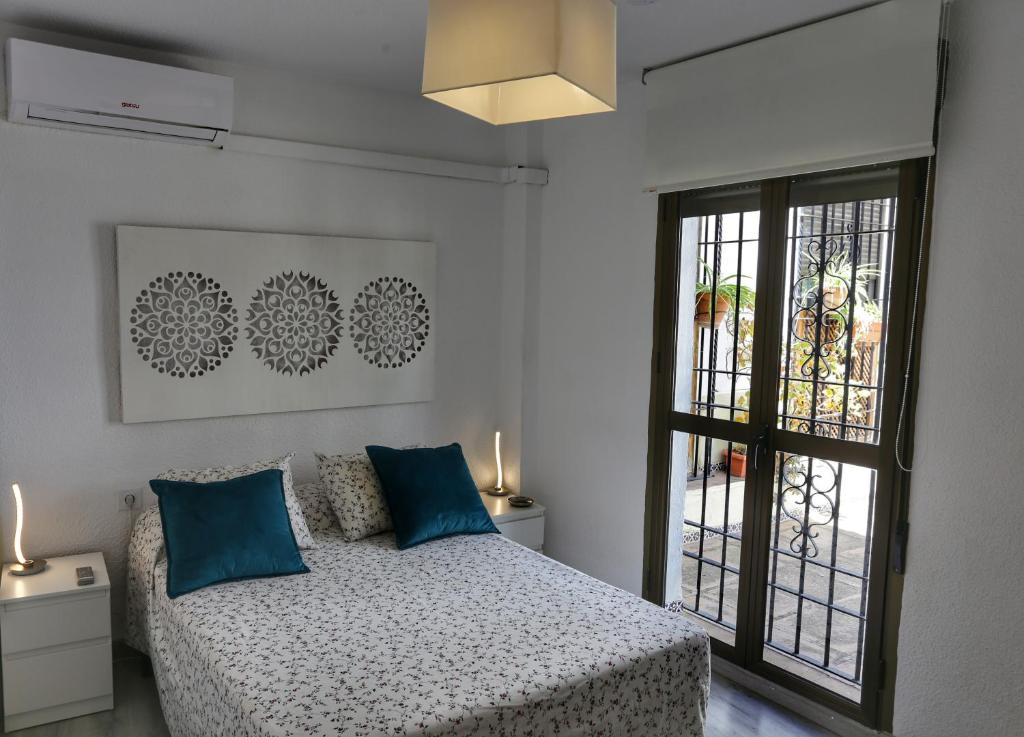 a bedroom with a bed with blue pillows and a window at Calle San Basilio - Patios. Aparcamiento gratis in Córdoba
