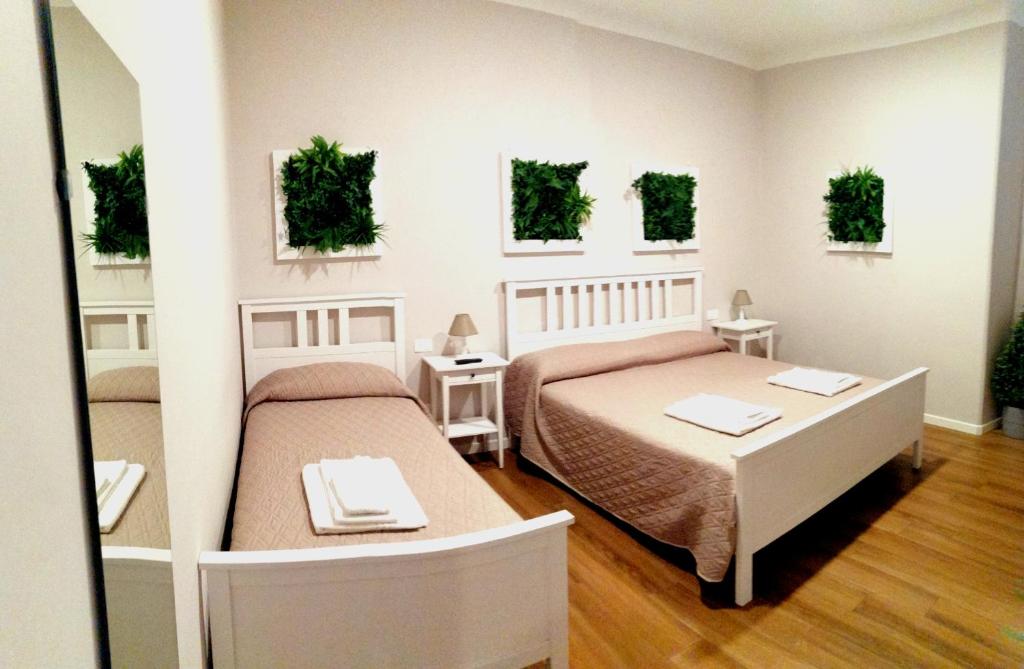 a bedroom with two beds and two tables and plants on the wall at Bixio Suites in La Spezia