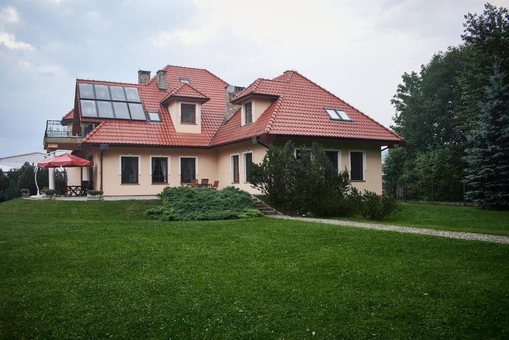 una casa con techo rojo en un patio verde en Willa Kosówka - Frydman, en Frydman