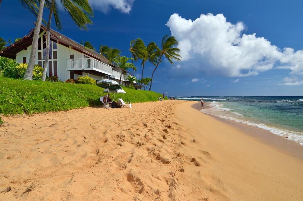 a sandy beach with a house and the ocean at Kiahuna Plantation 96, Poipu Beach, Athletic Club Membership, Part Ocean View in Koloa