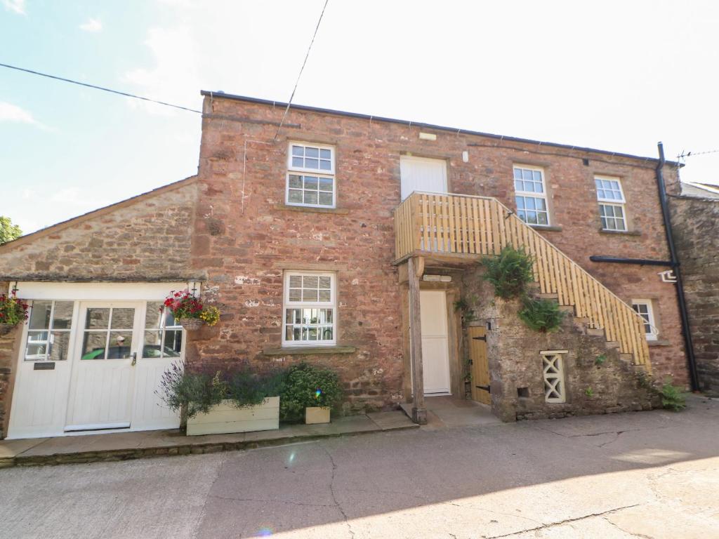 an old brick house with a white garage at Dairy Cottage in Kirkby Stephen