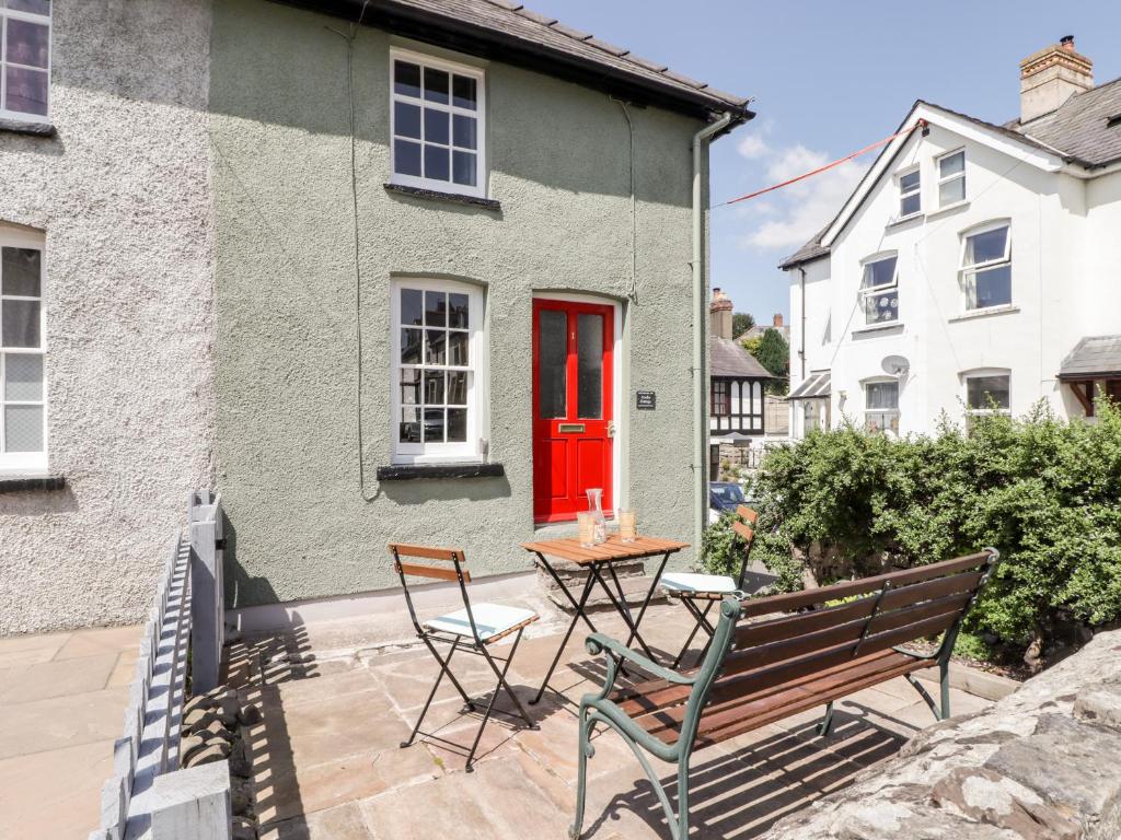 une maison avec une porte rouge, une table et des chaises dans l'établissement Kooky Cottage, à Brecon