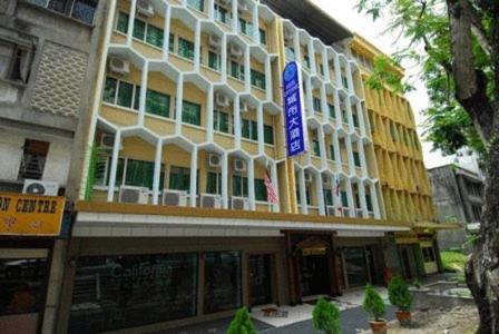 un edificio blanco y amarillo con un letrero azul en Hotel City Star, en Sandakan