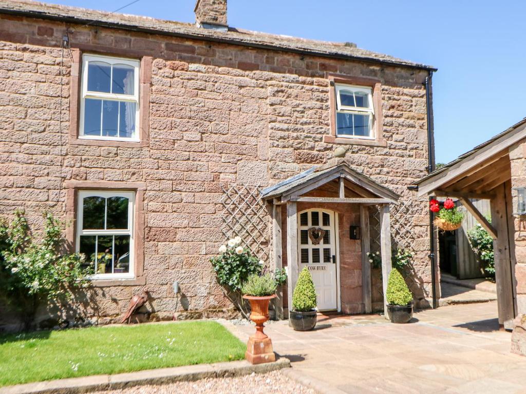 an old stone house with a white door at The Cow Byre in Kirkby Stephen