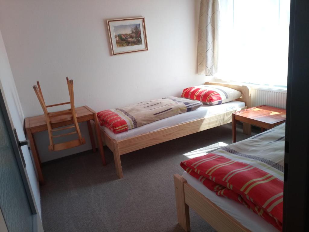 a room with two beds and a chair and a window at Penzion Athéna - sportovní areál in Nová Včelnice