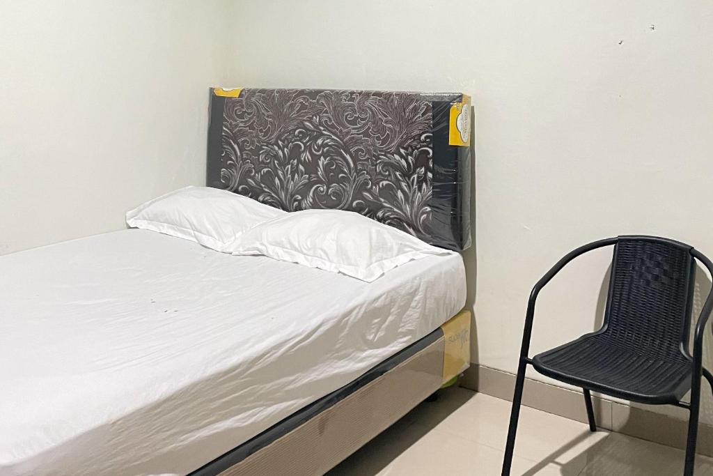 ein kleines Bett und ein Stuhl in einem Zimmer in der Unterkunft Almira Homestay Ambon Mitra RedDoorz in Ambon