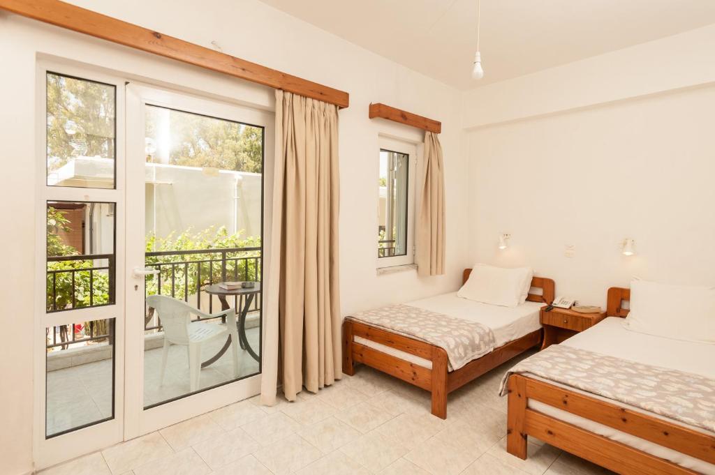 a bedroom with two beds and a balcony at Niriis Hotel in Kato Daratso