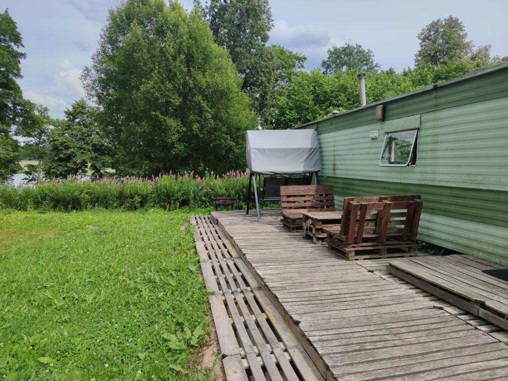 a wooden deck next to a green building at Luodžių dvaras in Salakas